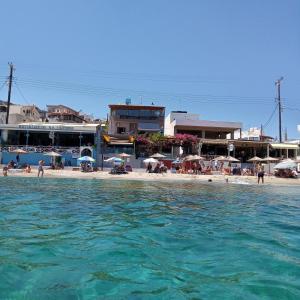 a beach with people and umbrellas in the water at Buganvilla Sea View apts in Agia Pelagia