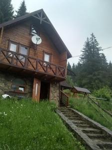 ein Blockhaus mit einer nebenstehenden Uhr in der Unterkunft Котеджі "У Яни" in Jablunyzja