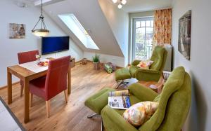 a living room with a table and green chairs at Haus EbenEzer in Büsum