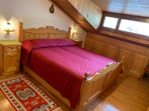 a bedroom with a wooden bed with a red comforter at Attico Vista Tofane in Cortina dʼAmpezzo