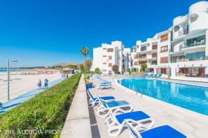 a swimming pool with lounge chairs in front of buildings at Apartamento Lortal in Alcudia