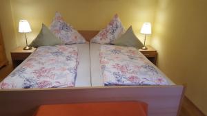 a bed with two pillows on it with two lamps at Am Berg-Ferienwohnung in Ettal +16 photos