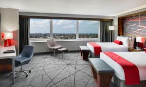 a hotel room with two beds and a desk and a window at Crowne Plaza JFK Airport New York City, an IHG Hotel in Queens