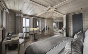 a bedroom with a large bed and a desk and a room at Hotel Le K2 Altitude in Courchevel