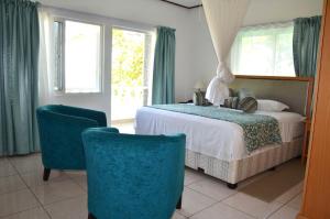 a bedroom with a bed and two blue chairs at Moonlight Beach Villa in La Digue