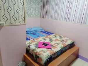 Una cama pequeña en una habitación con una carpeta rosa. en กอล์ฟ​&กิ๊ฟ​โฮม, en Phitsanulok