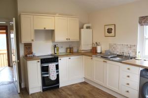 a kitchen with white cabinets and a black stove top oven at Hoveringham Hall in Nottingham