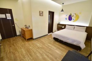 a bedroom with a bed and a wooden floor at Xiang Quie B&B in Taitung City