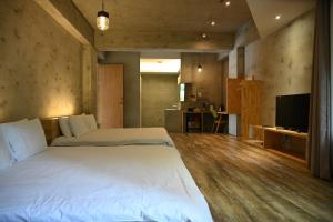 a bedroom with a large white bed and a television at 日月潭山慕藝旅 Sun Moon Inn in Yuchi