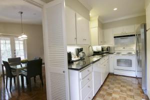 una cocina con armarios blancos y una mesa con sillas. en Tarrytown Townhouse en Austin