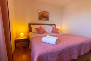 a bedroom with a bed with pink sheets and pillows at Apartments Vladimir #3 in Makarska