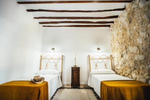 a bedroom with two beds and a stone wall at La Casa del Boticario in Alcalá del Júcar