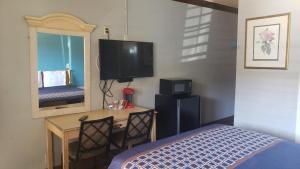 a bedroom with a bed and a desk and a mirror at Eagle Inn Motel in Long Beach
