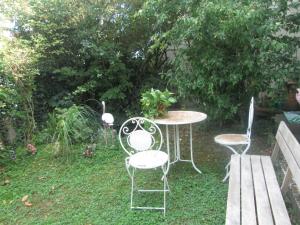 3 Stühle und ein Tisch im Hof mit einer Bank in der Unterkunft Appart Jungle in Clermont-Ferrand