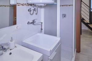 uma casa de banho branca com um lavatório e um espelho em La Palma Loft Located in the Heart of Catania em Catânia