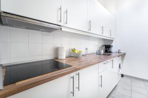 a kitchen with white cabinets and a wooden counter top at City Home Balaton in Siófok