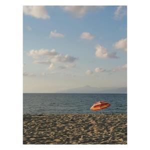 an orange umbrella sitting on a beach next to the ocean at Albergo Il Terrazzino in Vibo Valentia Marina