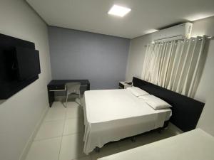 a bedroom with a bed and a desk and a television at Hotel Macapaba in Macapá