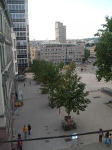 un grupo de personas caminando por una ciudad con edificios en Hotel am Wilhelmsplatz en Stuttgart