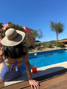 a woman in a hat sitting next to a swimming pool at Quinta Lorame in San Antonio de las Minas
