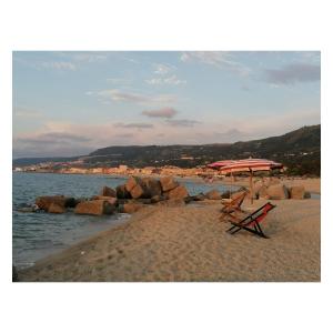 a beach with a chair and an umbrella on the sand at Albergo Il Terrazzino in Vibo Valentia Marina