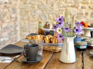 una mesa con una cesta de bollería y un jarrón de flores en L'Autre Maison, en Saint-Jean-de-Ceyrargues