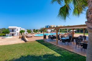 a patio with tables and chairs next to a pool at W Suites by Estia in Stalís