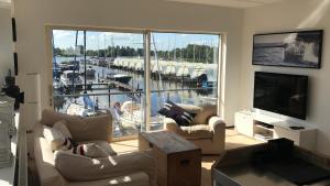 a living room with couches and a television and a marina at The Boathouse with boat in Aalsmeer