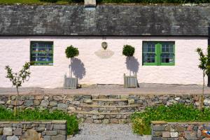 a white building with two windows and a green door at The Munches Room at Buittle Castle in Castle Douglas