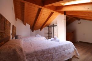 due letti in una stanza con soffitti in legno di Casas Rurales Bestue-Ordesa a Bestué