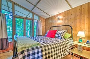 Ce lit se trouve dans un dortoir doté de murs en bois et de fenêtres. dans l'établissement Tranquil Mid-Century Modern Cottage with Forest View, à Hardy