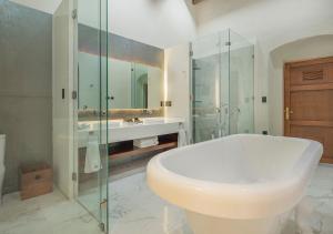 La salle de bains est pourvue d'une baignoire blanche et d'une douche en verre. dans l'établissement Casa Barroca, à Puebla