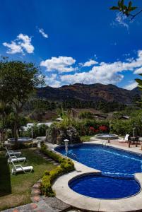 ein Schwimmbad in einem Garten mit Bergen im Hintergrund in der Unterkunft Hostería Paraíso in Vilcabamba