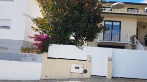 una cerca blanca frente a una casa con un árbol en Casa da Ribeira, en Aveiro