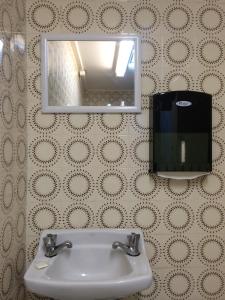uma casa de banho com um lavatório com um espelho e um dispensador de sabão em Central Private Hotel em Sydney