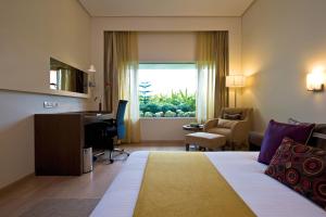 a hotel room with a bed and a desk and a window at The Gateway Hotel Beach Road Visakhapatnam in Visakhapatnam