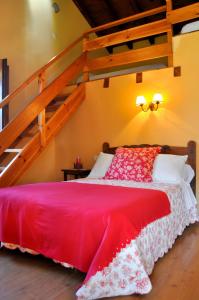 Un dormitorio con una cama roja y una escalera. en Casa Rural Los Llares, en Lerones 14 fotos más