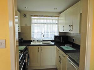 a kitchen with white cabinets and a sink and a window at Sheena's Dartmouth Chalets in Dartmouth