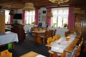 a restaurant with wooden tables and chairs and windows at Penzion u Lebedů in Kašperské Hory