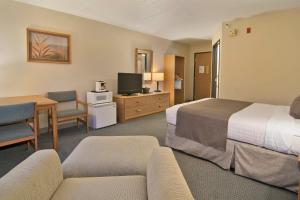 a hotel room with two beds and a couch and a desk at Boarders Inn & Suites by Cobblestone Hotels - Faribault in Faribault