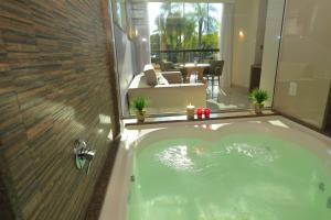 a bathroom with a tub and a glass shower at Vivaz Cataratas Hotel Resort in Foz do Iguaçu
