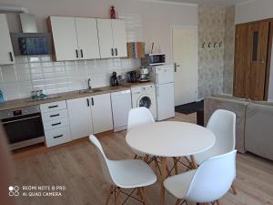 eine Küche mit weißen Schränken sowie einem Tisch und Stühlen in der Unterkunft Apartament Słoneczny in Augustów