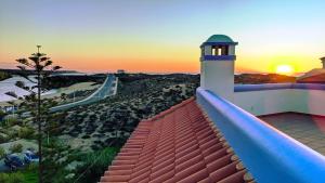 a lighthouse on a roof with the sunset in the background at Apartamentos Dunamar in Vila Nova de Milfontes