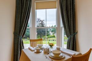 a dining room table with a large window at St Andrews House in Ballater