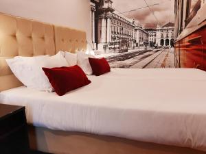 ein großes weißes Bett mit zwei roten Kissen darauf in der Unterkunft Lisbon City Apartments & Suites by City Hotels in Lissabon