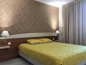 um quarto com uma cama com um edredão amarelo em Appartement Futuroscope-P' em Chasseneuil-du-Poitou