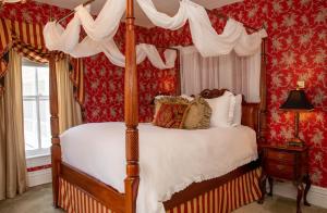a bedroom with a canopy bed with red wallpaper at Antrim 1844 in Taneytown