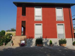 a red building with white doors and potted plants at bellaria in Voghera
