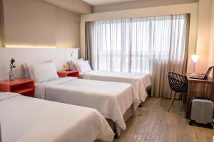 a hotel room with two beds and a window at Intercity Curitiba Centro Cívico in Curitiba