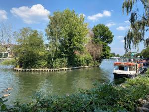 a boat on a river with trees on the side at Letting Serviced Apartments - Guards View, Windsor in Windsor